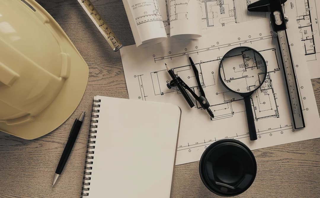 Blueprints, drafting tools and a hard hat on a desk